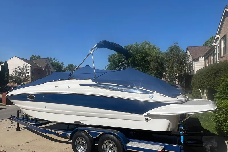 The Image of 2006 Crownline 252 EX boat on trailer, covered, parked in residential area. - 1