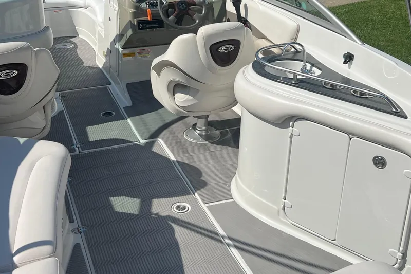 Slide: The Image of Interior of a 2006 Crownline 252 EX boat, featuring seating and a compact kitchenette. - 10