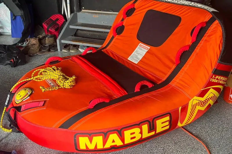 Slide: The Image of Bright orange inflatable water tube labeled "Mable" with rope, in a garage setting. - 15