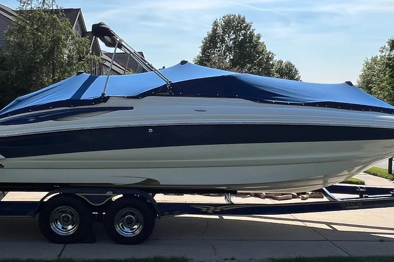 Slide: The Image of 2006 Crownline 252 EX boat on trailer with blue cover, parked in driveway. - 3