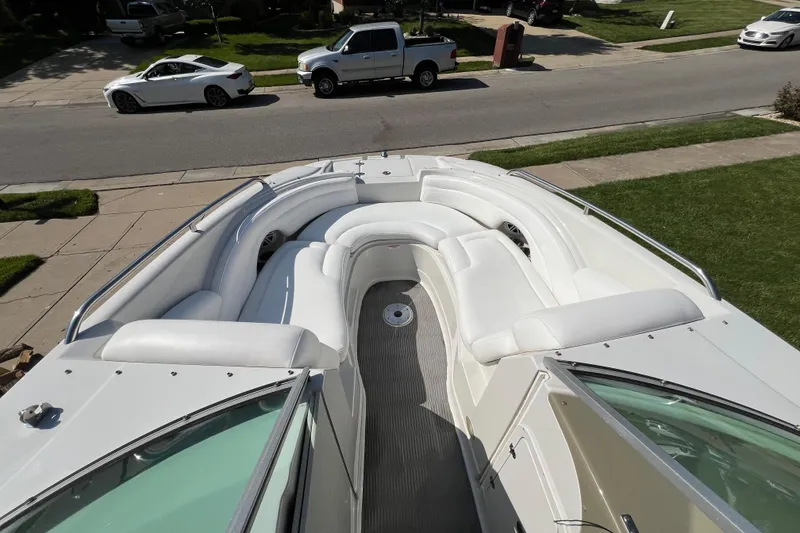 Slide: The Image of 2006 Crownline 252 EX boat with spacious white seating, parked in a suburban neighborhood. - 6