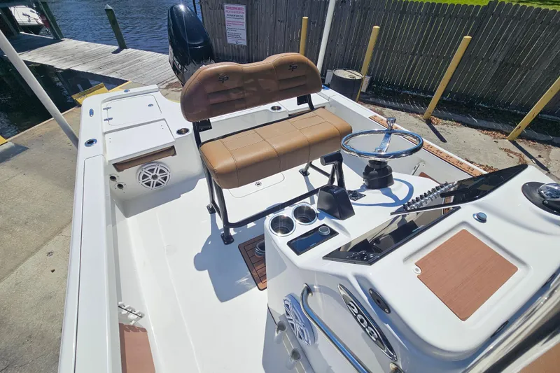Slide: The Image of 2019 Sea Pro 208 Bay boat interior with steering wheel and seating, docked by the water. - 12