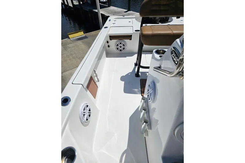 Slide: The Image of 2019 Sea Pro 208 Bay boat interior with seating and speakers, docked by the water. - 21