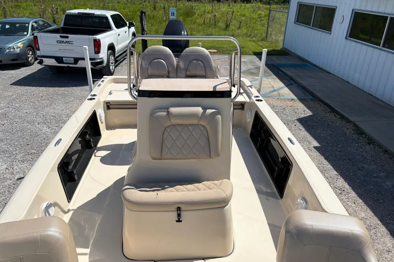 Slide: The Image of 2018 Blue Wave 2200 PureBay boat interior with seating and console, parked near vehicles. - 9