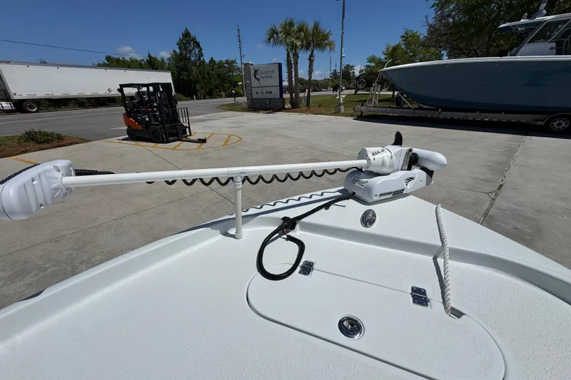 Slide: The Image of 2016 Yellowfin 21 Hybrid boat with trolling motor on deck, parked outdoors. - 21