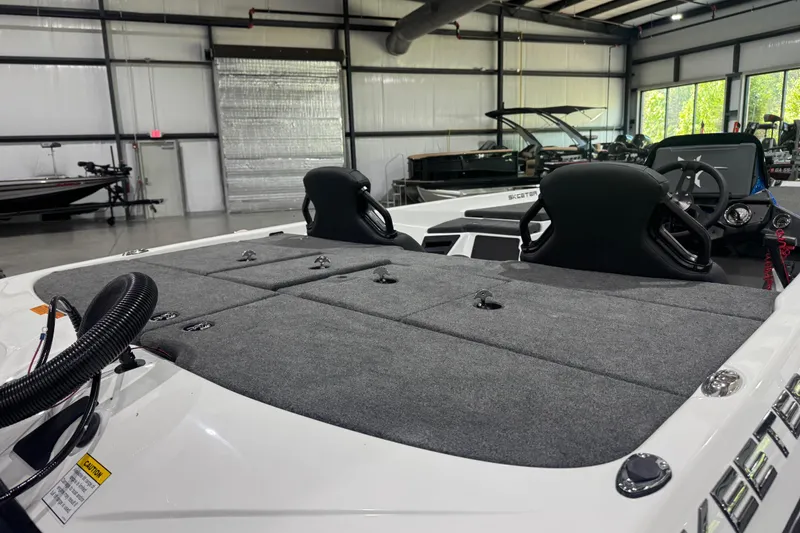 Slide: The Image of 2026 Skeeter ZXR21 SE boat interior with dual seats and carpeted deck in showroom. - 10