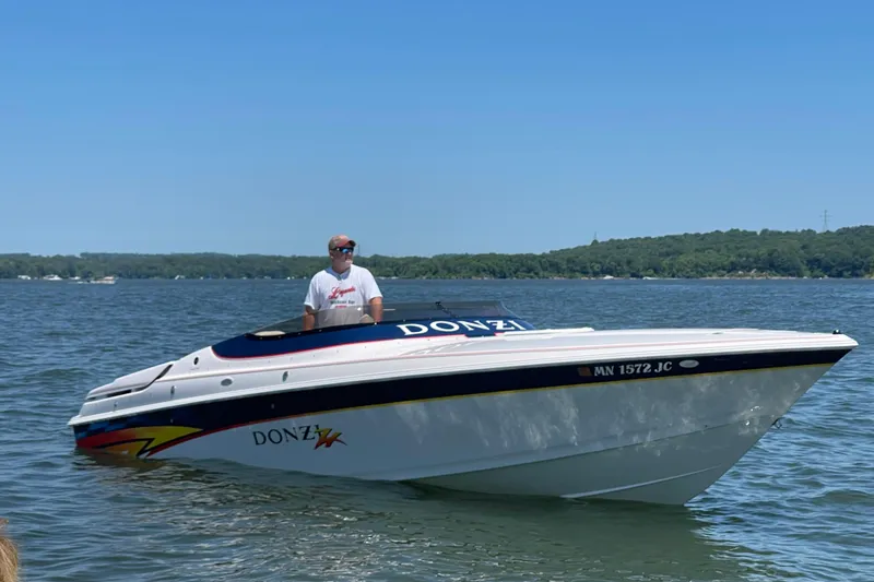 Slide: The Image of 2001 Donzi 28 ZX speedboat on a lake with a person at the helm. - 2