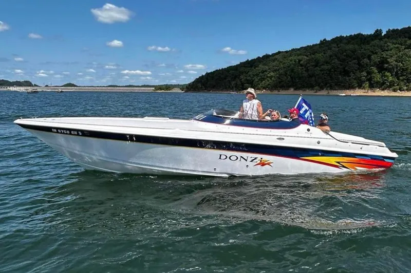 Slide: The Image of 2001 Donzi 28 ZX speedboat cruising on a lake with passengers, clear skies, and scenic background. - 9