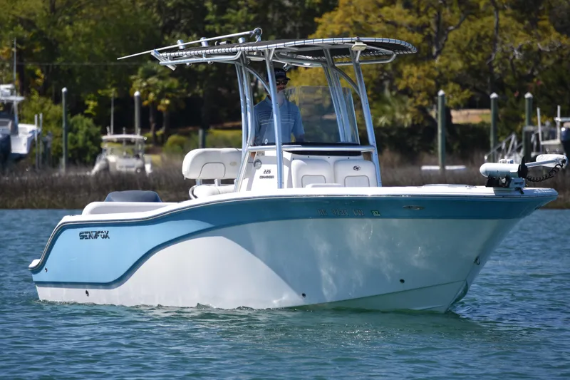 The Image of 2014 Sea Fox 226 Commander boat cruising on calm water with lush greenery in the background. - 2
