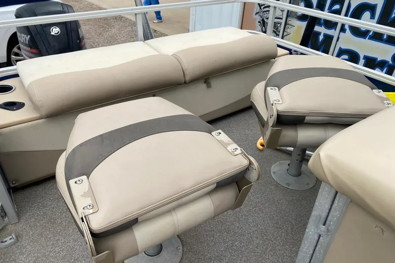 Slide: The Image of 2016 Sun Tracker Fishin' Barge 22 DLX interior with beige seating and fishing chairs. - 13