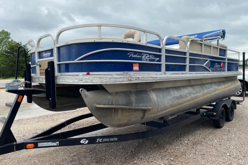 Slide: The Image of 2016 Sun Tracker Fishin' Barge 22 DLX pontoon boat on trailer, parked outdoors. - 3
