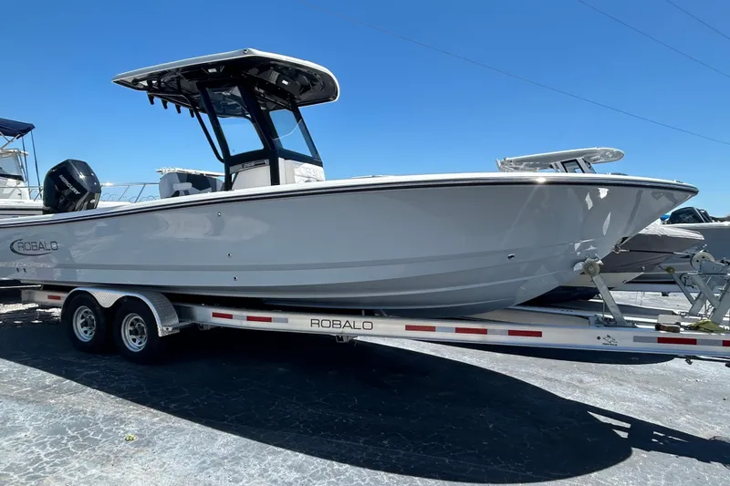 The Image of 2025 Robalo 266 Cayman boat on trailer under clear blue sky. - 0
