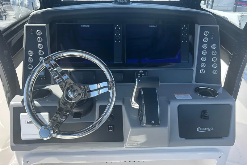Slide: The Image of 2025 Robalo 266 Cayman boat dashboard with steering wheel and Simrad displays. - 12