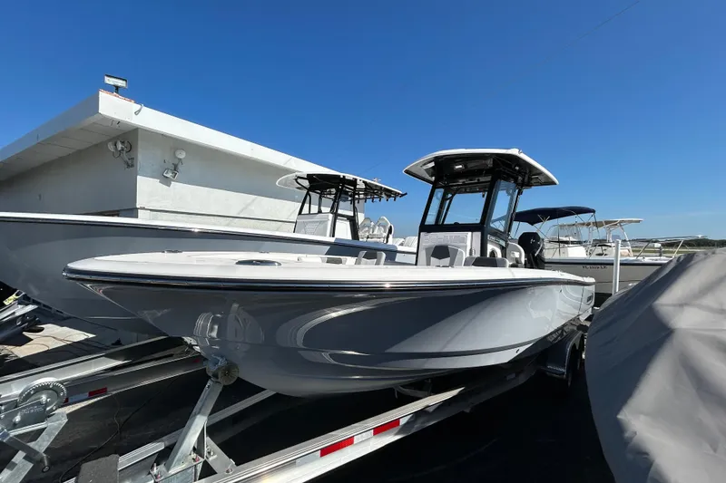 Slide: The Image of 2025 Robalo 266 Cayman boat on trailer, displayed outdoors under clear blue sky. - 16