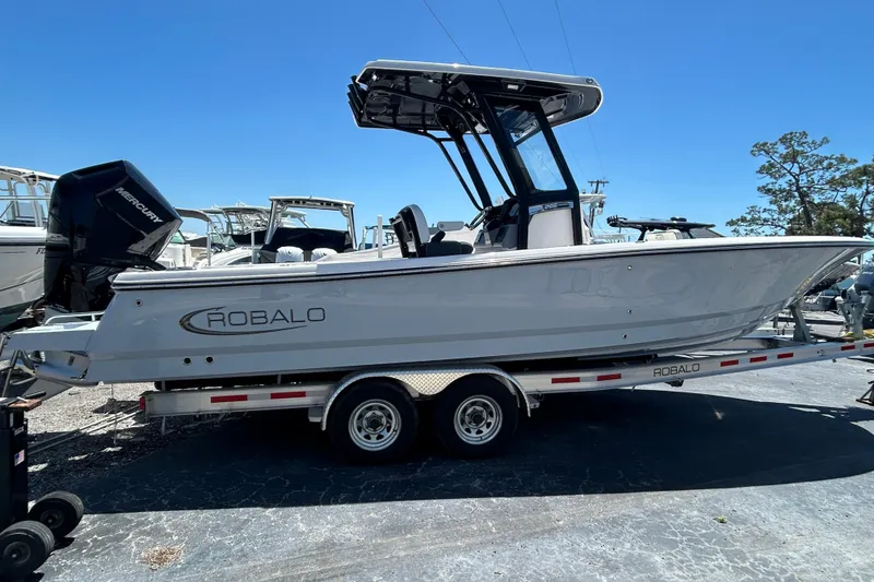 Slide: The Image of 2025 Robalo 266 Cayman boat on trailer, side view under clear blue sky. - 2