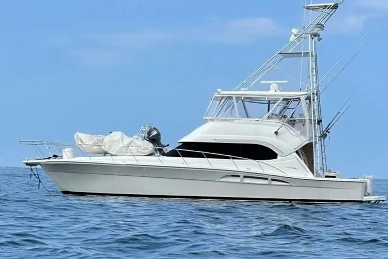 The Image of 2004 Riviera 51 Flybridge yacht on open water under clear blue sky. - 0