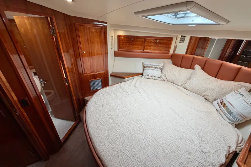 Slide: The Image of Luxurious 2004 Riviera 51 Flybridge cabin with cozy bed and elegant wood finishes. - 19