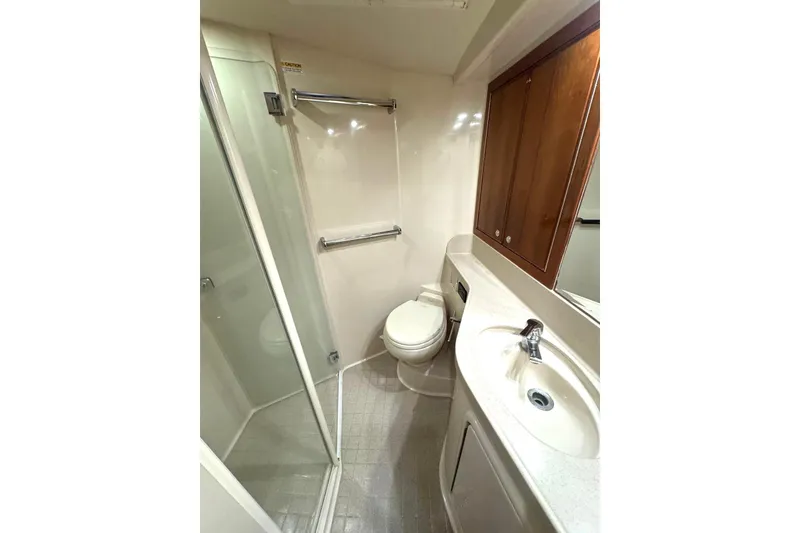 Slide: The Image of Bathroom interior of 2004 Riviera 51 Flybridge yacht, featuring shower, toilet, and sink. - 16