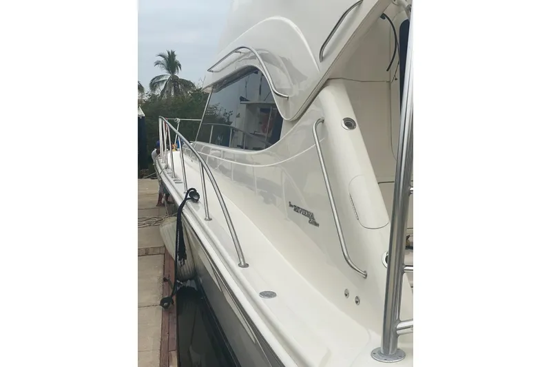 Slide: The Image of 2004 Riviera 51 Flybridge yacht, sleek design, docked with palm trees in background. - 3