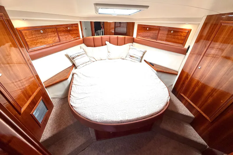 Slide: The Image of Luxurious 2004 Riviera 51 Flybridge yacht bedroom with elegant wood finishes and cozy bedding. - 18