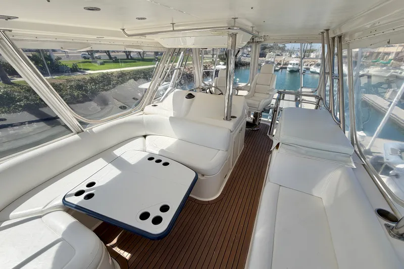 Slide: The Image of Luxurious 2004 Riviera 51 Flybridge interior with seating and helm, overlooking marina. - 25