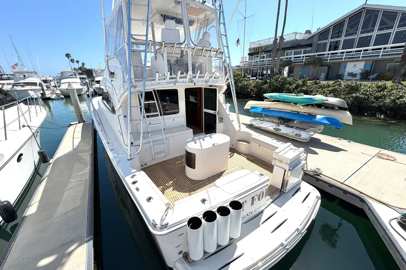 Slide: The Image of 2004 Riviera 51 Flybridge yacht docked at marina, featuring spacious deck and fishing rod holders. - 2
