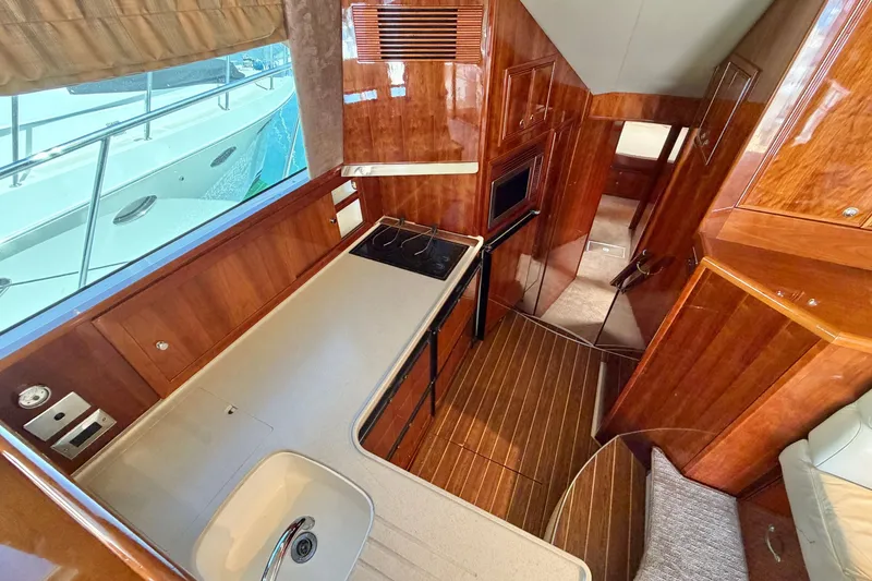 Slide: The Image of Luxurious 2004 Riviera 51 Flybridge yacht interior with sleek wooden finishes and modern kitchen amenities. - 17