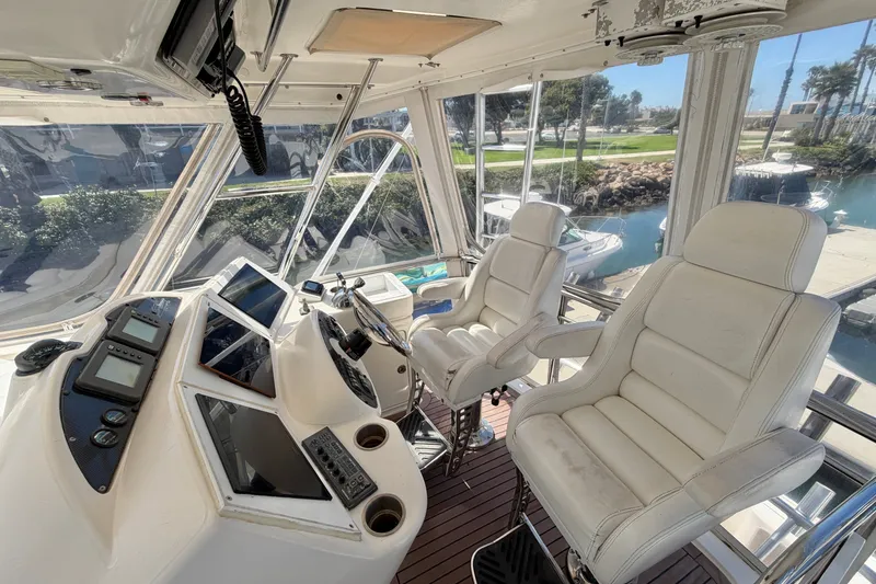 Slide: The Image of Interior of 2004 Riviera 51 Flybridge yacht with helm and white captain chairs. - 27