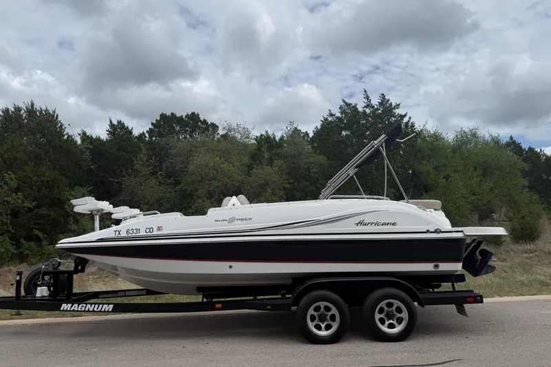 Slide: The Image of 2014 Hurricane SunDeck Sport 202 IO boat on trailer, parked on roadside with trees in background. - 11