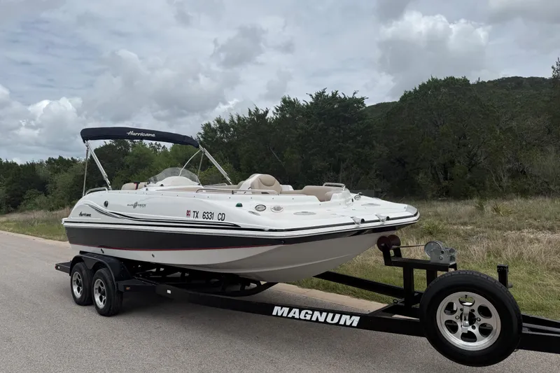 Slide: The Image of 2014 Hurricane SunDeck Sport 202 IO boat on trailer, parked roadside with trees in background. - 13