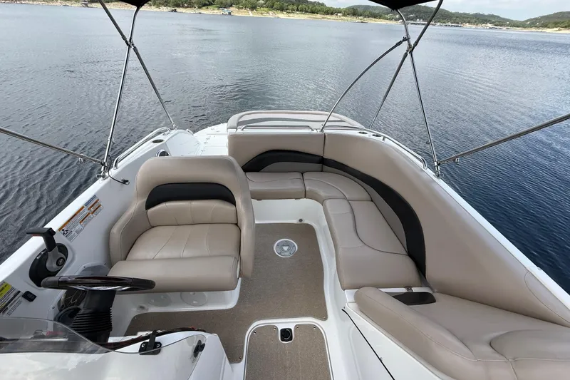 Slide: The Image of 2014 Hurricane SunDeck Sport 202 IO boat interior with seating and steering wheel on calm water. - 23