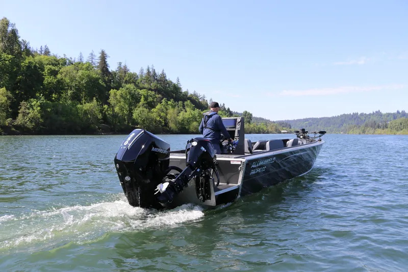Slide: The Image of 2026 Alumaweld Pacific CC 26 boat cruising on a scenic lake with lush green surroundings. - 1