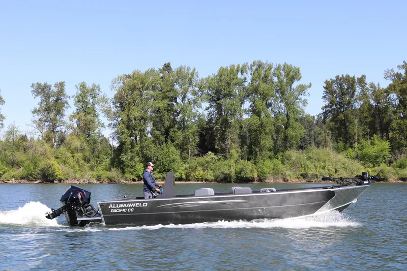 The Image of 2026 Alumaweld Pacific CC 26 boat cruising on a scenic river with lush green trees. - 0