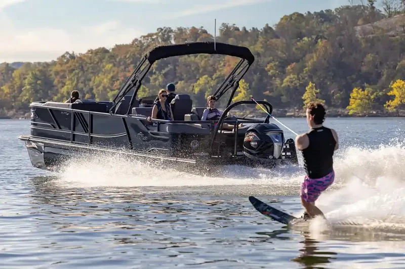 Slide: The Image of Manufacturer Provided Image: 2026 SunCatcher Elite 324 SS boat towing a water skier on a scenic lake. - 17