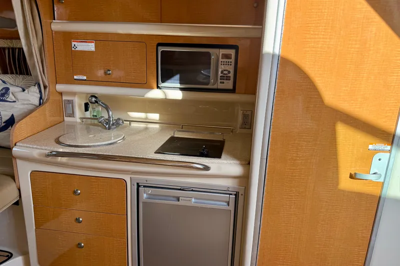 Slide: The Image of 2006 Chaparral Signature 290 boat kitchen with sink, microwave, and mini fridge. - 11