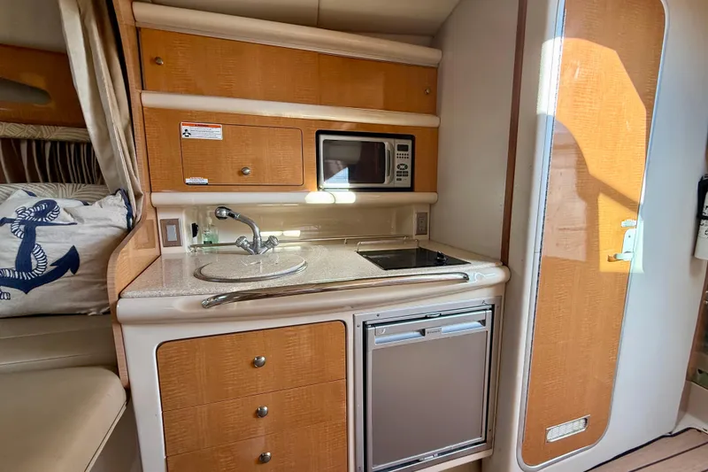 Slide: The Image of 2006 Chaparral Signature 290 boat interior with kitchenette, featuring sink, microwave, and mini-fridge. - 18