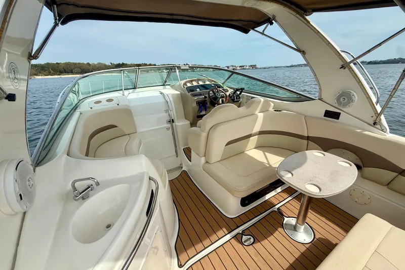 Slide: The Image of 2006 Chaparral Signature 290 boat interior with seating, table, and helm, on calm water. - 2