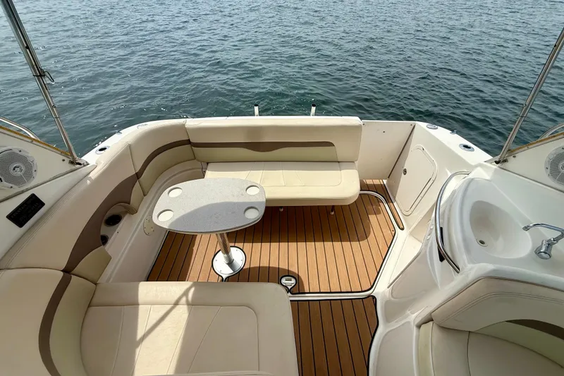 Slide: The Image of 2006 Chaparral Signature 290 boat interior with seating, table, and sink on water. - 25