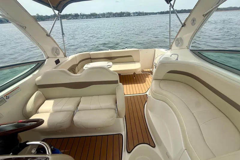 Slide: The Image of 2006 Chaparral Signature 290 boat interior with beige seating and wood flooring on a lake. - 3