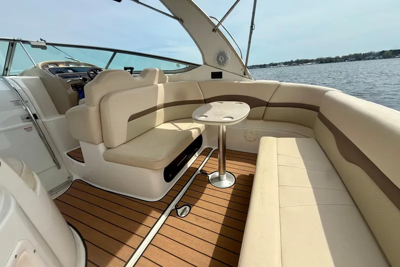 Slide: The Image of 2006 Chaparral Signature 290 boat interior with beige seating and wooden flooring, overlooking water. - 5