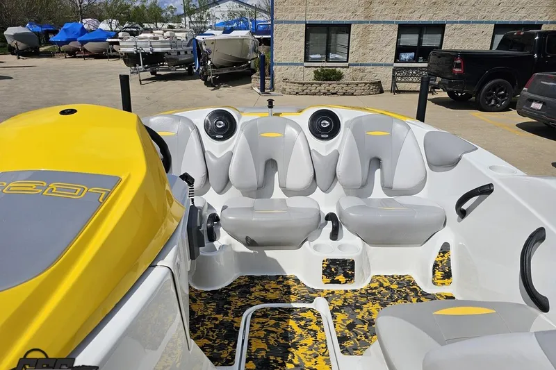 Slide: The Image of 2007 Sea-Doo 150 Speedster boat interior with yellow and gray seating, parked outdoors. - 77