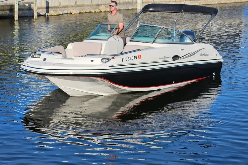 The Image of 2013 Hurricane SunDeck 217 OB boat cruising on calm water with a person at the helm. - 0