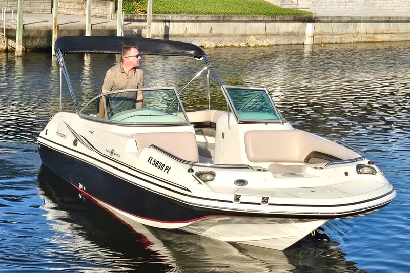 Slide: The Image of 2013 Hurricane SunDeck 217 OB boat on water with a person steering. - 2
