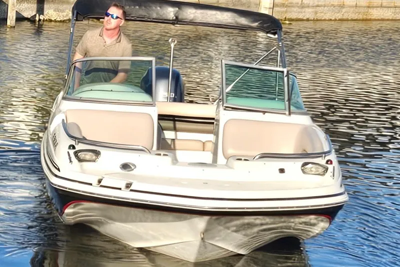 Slide: The Image of 2013 Hurricane SunDeck 217 OB boat on water with driver, featuring open deck and windshield. - 5