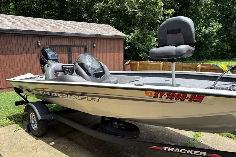 Slide: The Image of 2024 Bass Tracker Pro 17 boat on trailer, parked near a wooden shed. - 12