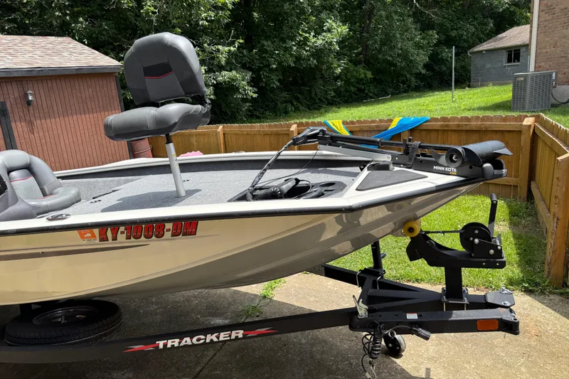 Slide: The Image of 2024 Bass Tracker Pro 17 boat on trailer, parked in a driveway with lush greenery. - 13