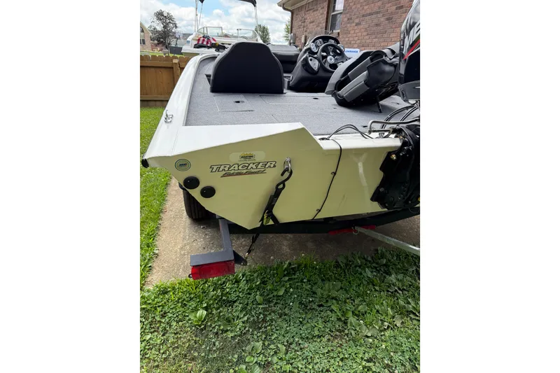 Slide: The Image of 2024 Bass Tracker Pro 17 boat, rear view, parked on grass beside a brick building. - 14