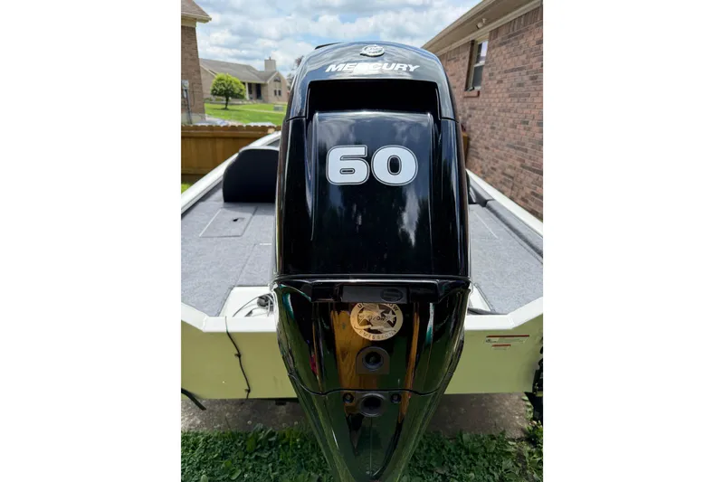 Slide: The Image of 2024 Bass Tracker Pro 17 with Mercury 60 outboard motor in a residential setting. - 16