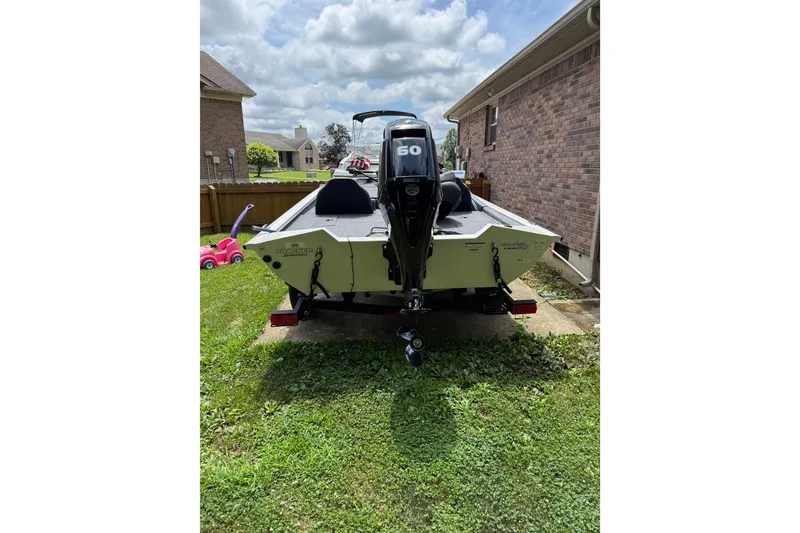 Slide: The Image of 2024 Bass Tracker Pro 17 boat with 60 HP motor parked in a residential yard. - 17