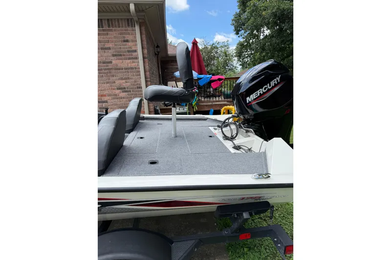 Slide: The Image of 2024 Bass Tracker Pro 17 boat with Mercury engine, parked near a brick house. - 4